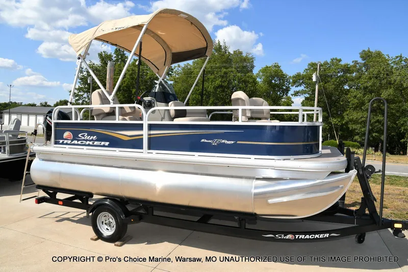 Slide: The Image of 2025 Sun Tracker Bass Buggy 16 XL Select pontoon boat on trailer, outdoor setting. - 43