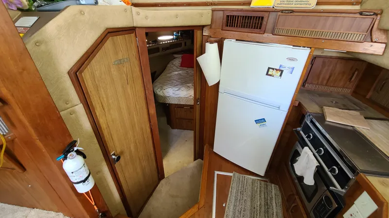 Slide: The Image of 1983 Sea Ray 360 Aft Cabin interior with kitchen, fridge, and bedroom view. - 15