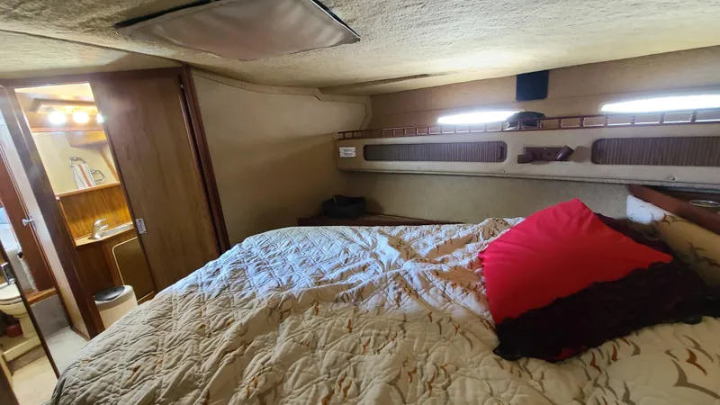Slide: The Image of 1983 Sea Ray 360 Aft Cabin interior with bed, red pillow, and adjacent bathroom. - 18