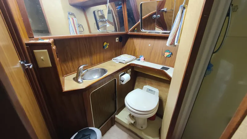 Slide: The Image of 1983 Sea Ray 360 Aft Cabin bathroom with wood paneling, sink, and toilet. - 19