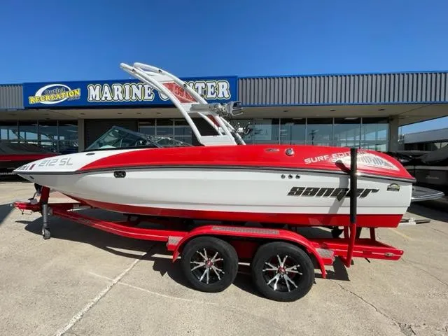 Slide: The Image of 2015 Sanger V 212 boat on a red trailer outside a marine center. - 2