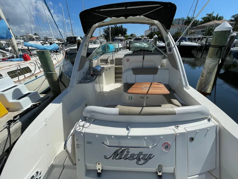 Slide: The Image of 2007 Sea Ray 310 Sundancer boat docked, featuring spacious seating and a wooden table. - 11