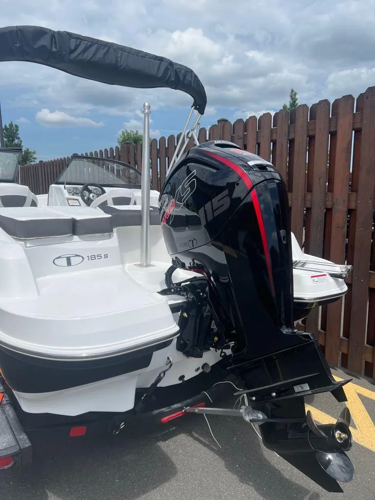 Slide: The Image of 2024 Tahoe 185 S boat with outboard motor, docked near wooden fence. - 6