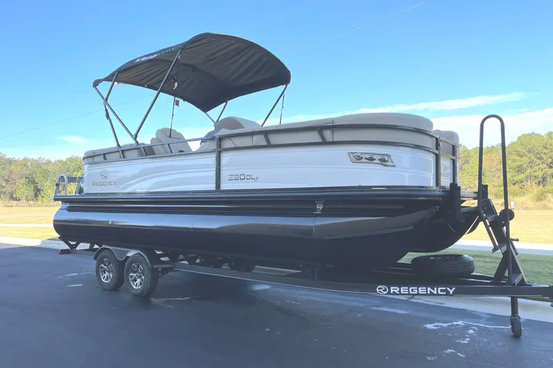 Slide: The Image of 2024 Regency 230 DL3 pontoon boat on a trailer with canopy. - 0