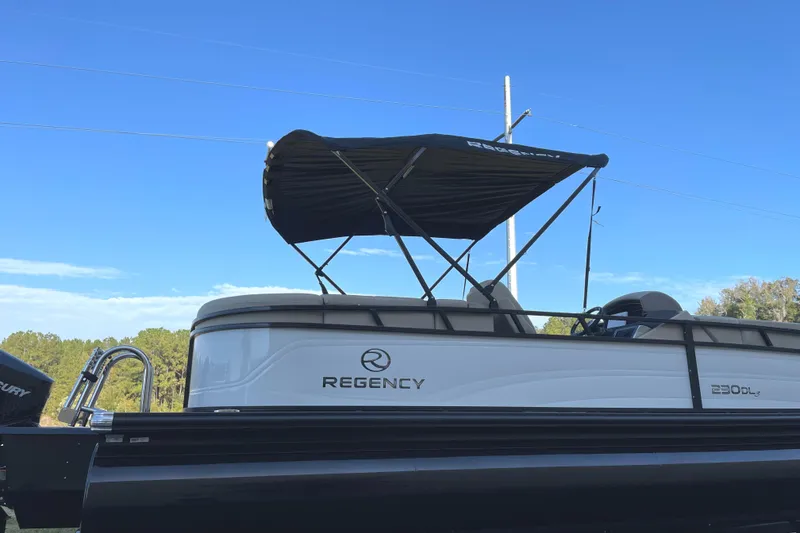 Slide: The Image of 2024 Regency 230 DL3 pontoon boat with canopy against blue sky. - 3