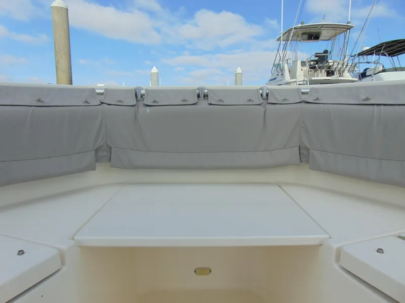 Slide: The Image of 2016 Cobia 237 Center Console boat interior with gray seating, docked under a blue sky. - 13