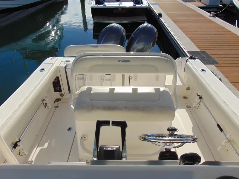 Slide: The Image of 2016 Cobia 237 Center Console boat interior with steering wheel and seating at dock. - 34