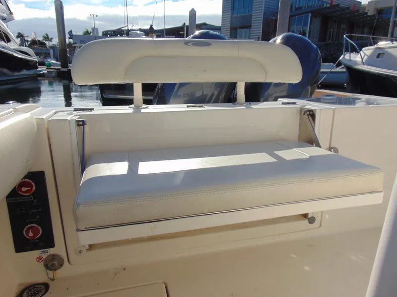 Slide: The Image of 2016 Cobia 237 Center Console boat seat at marina, featuring white cushioned seating. - 5