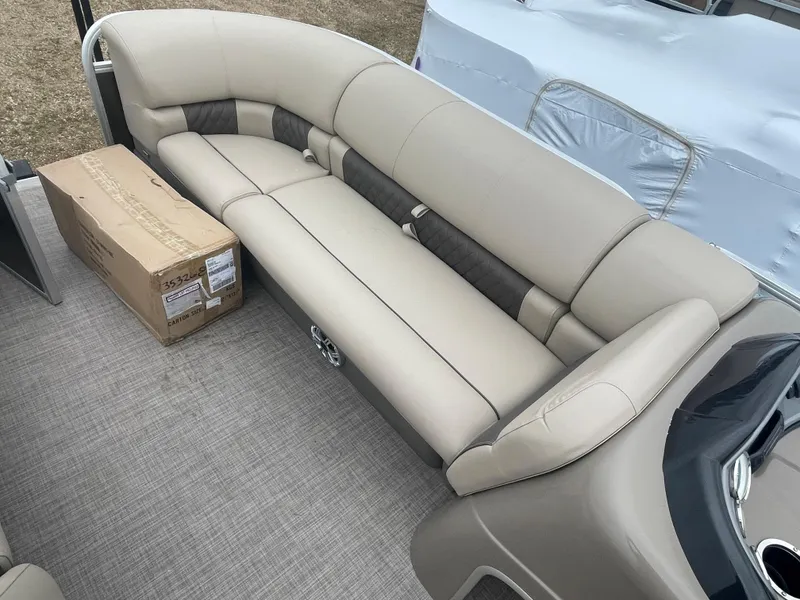 Slide: The Image of 2023 Sun Tracker Party Barge 20 DLX interior with beige seating and a cardboard box. - 10
