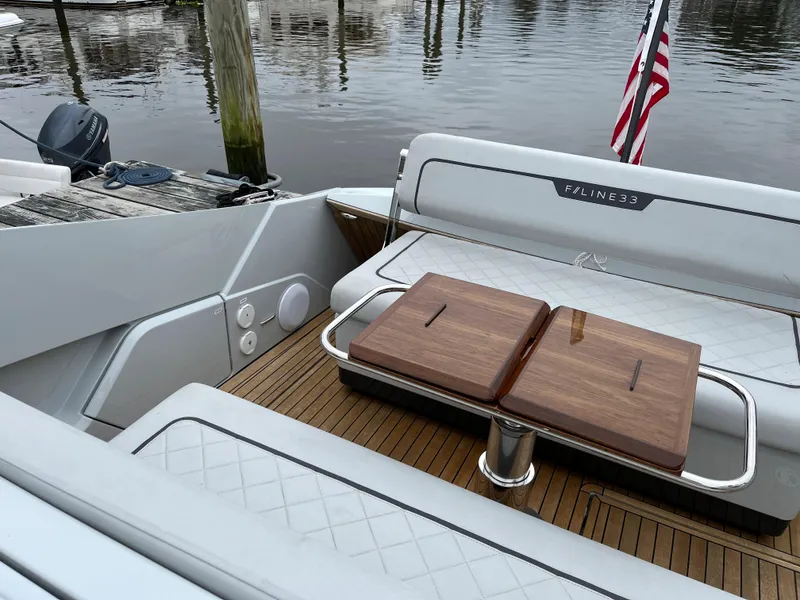 Slide: The Image of 2022 Fairline F//Line 33 yacht interior with wooden table and seating, docked by the water. - 8
