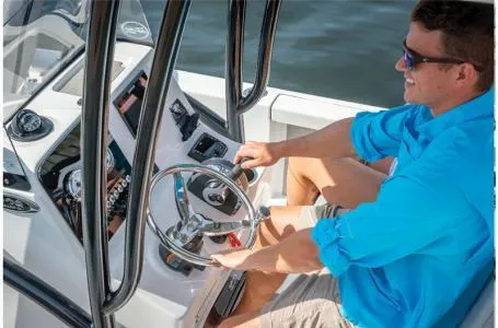 Slide: The Image of 2023 Sea Pro 208 Bay Boat with T-Top, man steering on open water. - 11