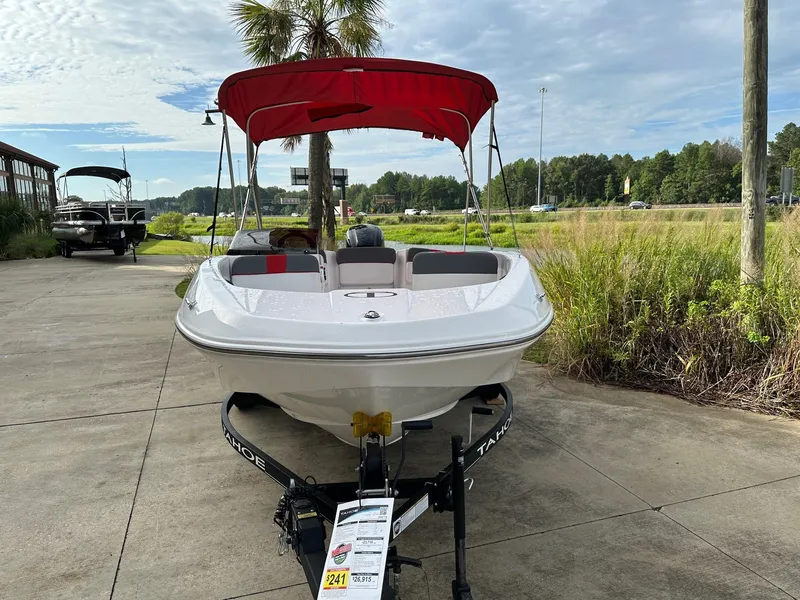 Slide: The Image of 2024 Tahoe T16 boat with red canopy on trailer, parked outdoors. - 2