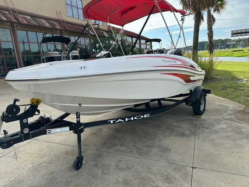 Slide: The Image of 2024 Tahoe T16 boat with red canopy on trailer, parked outdoors. - 3