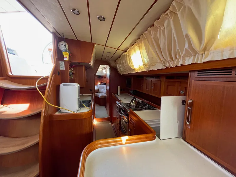 Slide: The Image of Interior of 2009 Hallberg-Rassy 54 yacht, featuring a cozy kitchen and wooden cabinetry. - 21