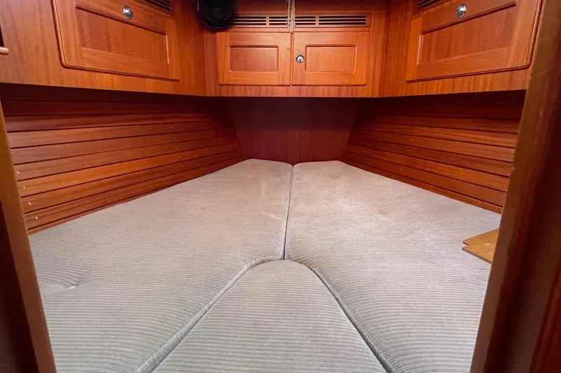 Slide: The Image of Interior cabin of 2009 Hallberg-Rassy 54 yacht with wooden paneling and cushioned bed. - 24