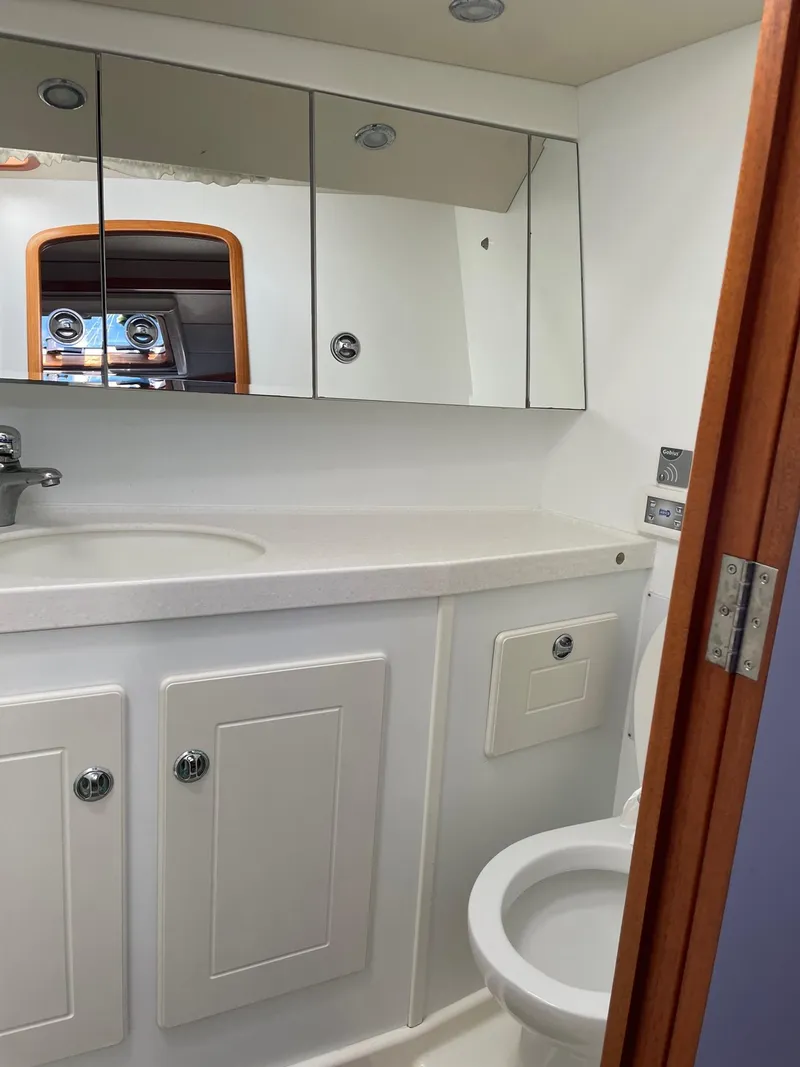 Slide: The Image of Bathroom interior of 2009 Hallberg-Rassy 54 yacht, featuring white cabinetry and mirrored storage. - 26