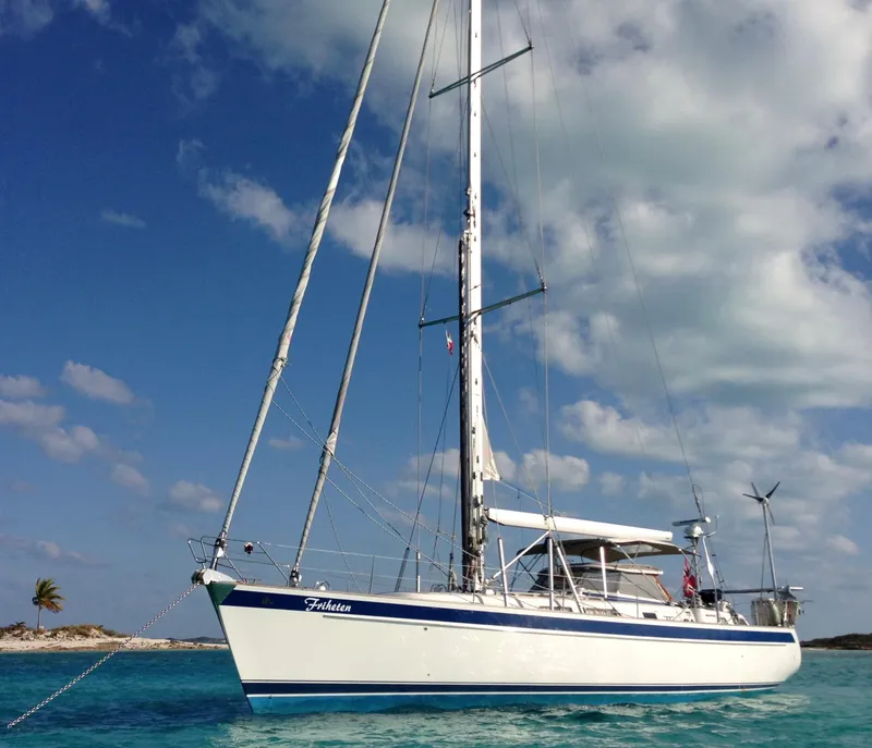 Slide: The Image of 2009 Hallberg-Rassy 54 sailboat anchored in clear blue waters under a partly cloudy sky. - 3