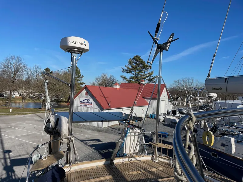 Slide: The Image of 2009 Hallberg-Rassy 54 yacht docked near a marina with red-roofed building. - 37
