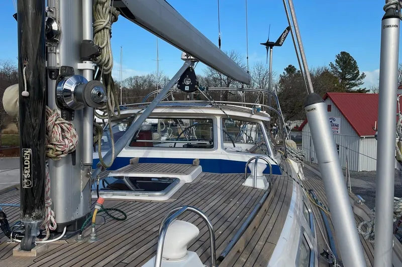 Slide: The Image of 2009 Hallberg-Rassy 54 sailboat deck with mast and rigging, docked near red-roofed building. - 45