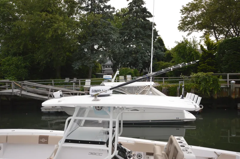 Slide: The Image of 2017 Fountain 38 Center Console boat docked near a wooden pier with lush greenery. - 20
