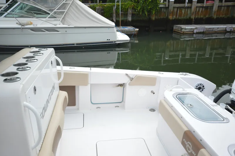 Slide: The Image of 2017 Fountain 38 Center Console boat interior at dock, featuring seating and storage compartments. - 31