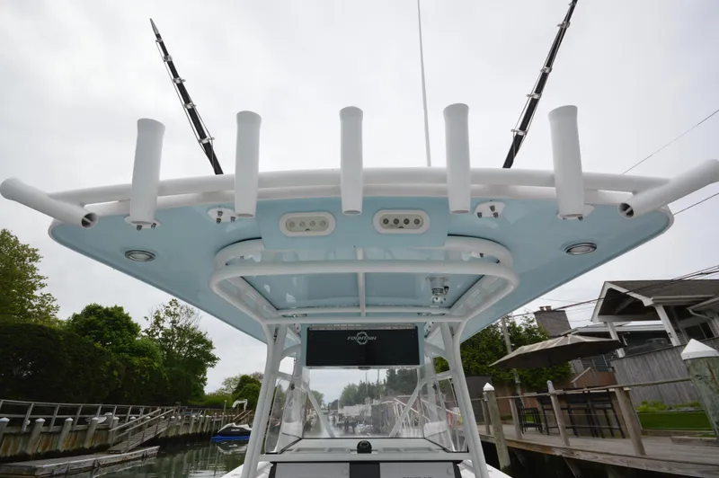 Slide: The Image of 2017 Fountain 38 Center Console boat with rod holders and canopy, docked near waterfront homes. - 9