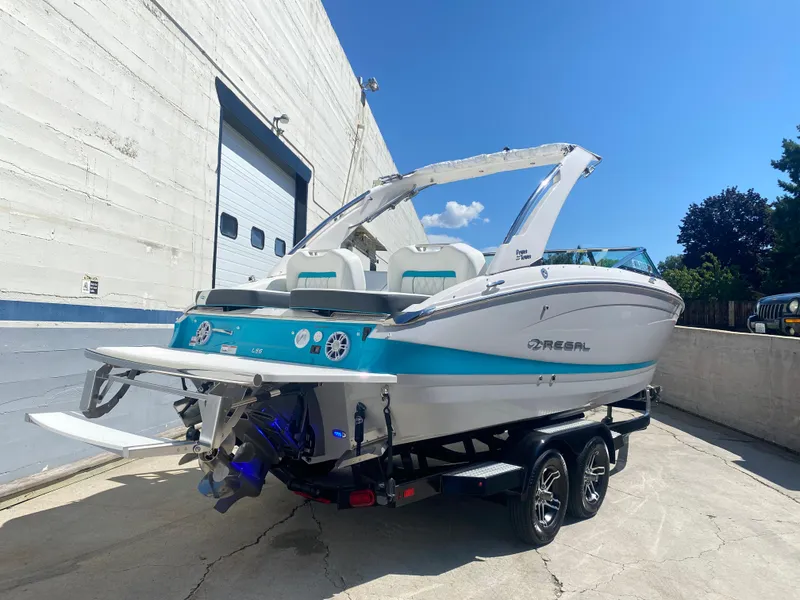 Slide: The Image of 2024 Regal LS6 boat on trailer, white and blue, docked outdoors. - 15