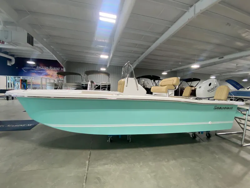 Slide: The Image of 2024 Savannah SS19 boat in showroom, light blue hull, beige seating. - 0