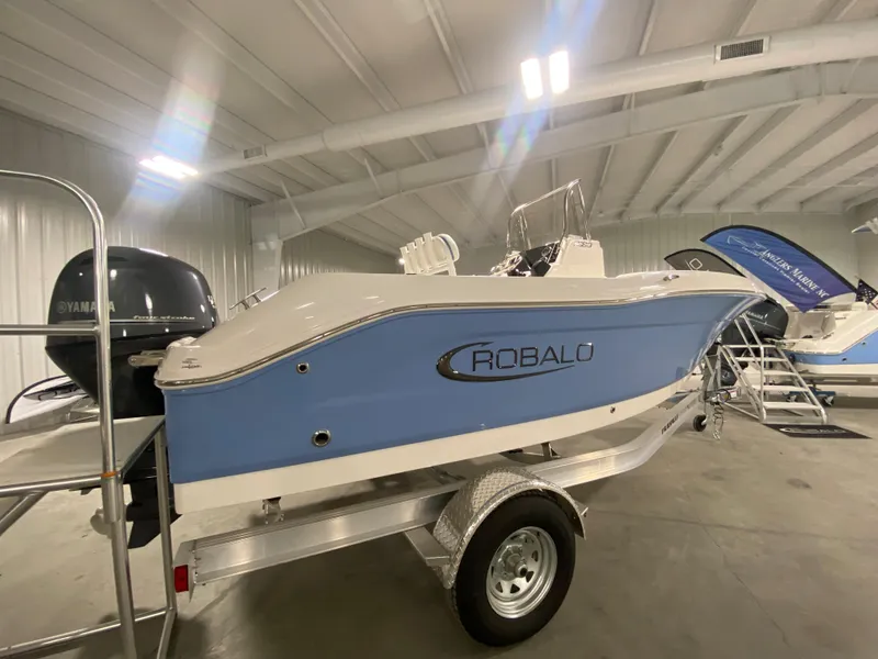 Slide: The Image of 2024 Robalo R180 Center Console boat on trailer in indoor showroom. - 2