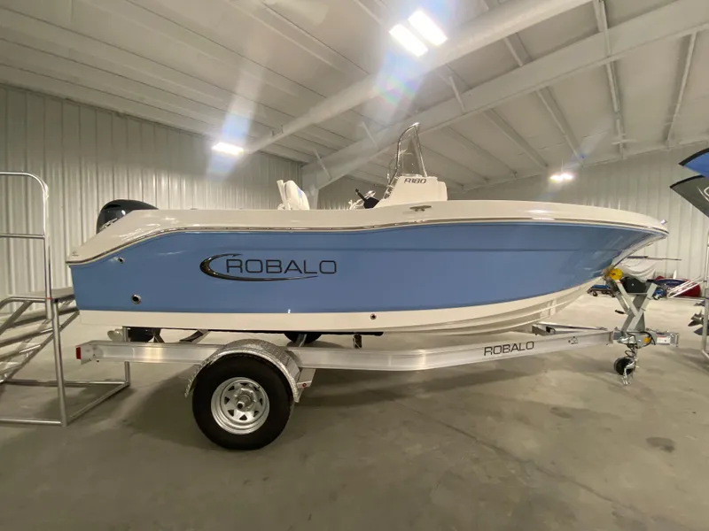 Slide: The Image of 2024 Robalo R180 Center Console boat on trailer in indoor storage. - 0