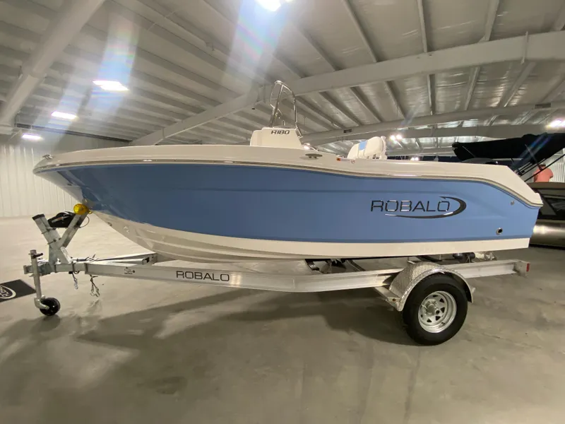 Slide: The Image of 2024 Robalo R180 Center Console boat on trailer in indoor showroom. - 1