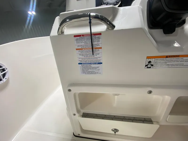 Slide: The Image of 2024 Robalo R180 Center Console boat interior with safety labels and storage compartment. - 12