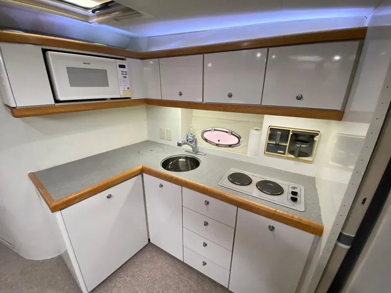 Slide: The Image of 1996 Carver 390 Express yacht kitchen with microwave, sink, stove, and storage cabinets. - 21