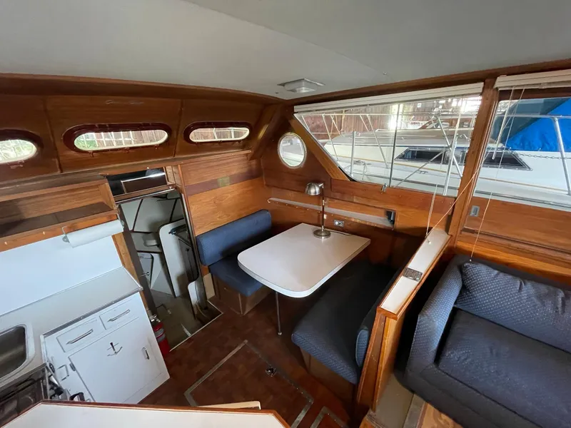 Slide: The Image of 1961 Chris-Craft Conqueror interior with wooden paneling, dining area, and compact kitchen. - 21