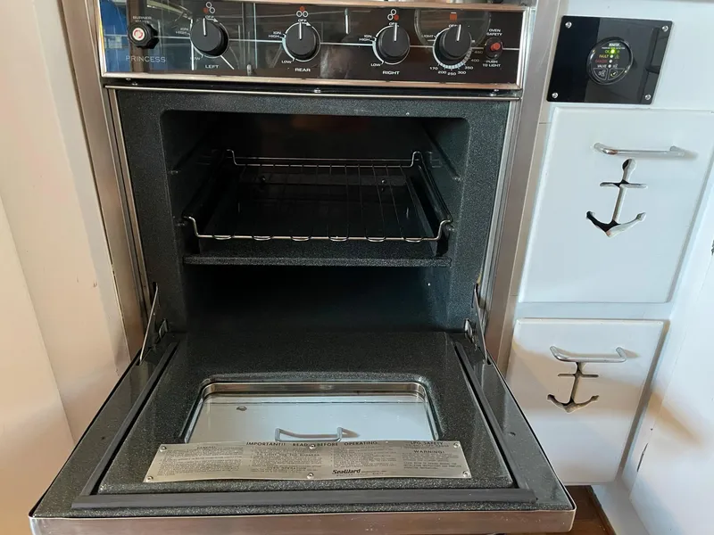 Slide: The Image of 1961 Chris-Craft Conqueror oven with open door, control knobs, and anchor-themed cabinetry. - 23