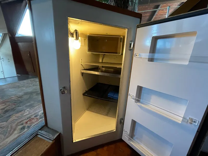 Slide: The Image of Open refrigerator inside a 1961 Chris-Craft Conqueror boat, showcasing interior shelves and light. - 33