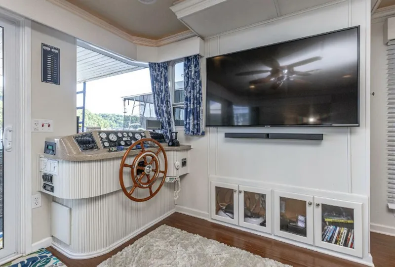 Slide: The Image of Helm station of a 2007 Horizon 18 x 80 houseboat with a large TV and wooden steering wheel. - 4