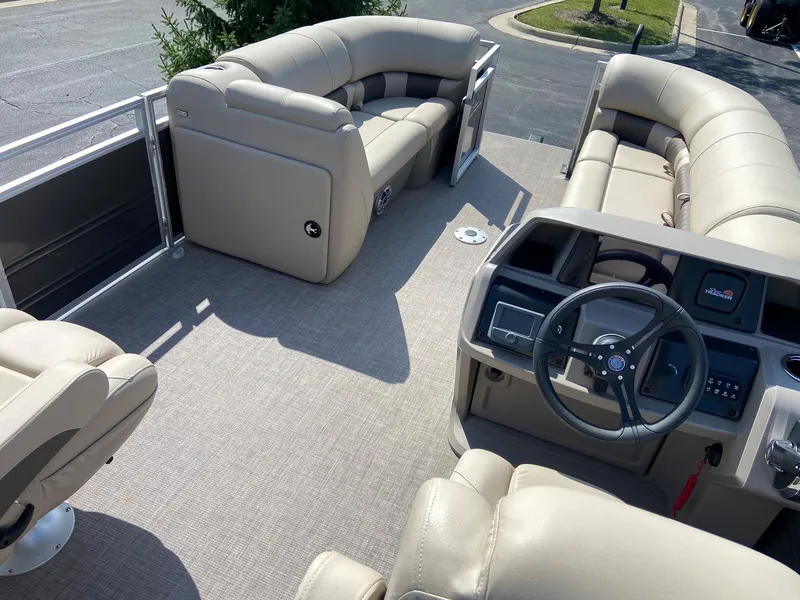 Slide: The Image of 2024 Sun Tracker Party Barge 22 DLX interior with beige seating and steering console. - 5