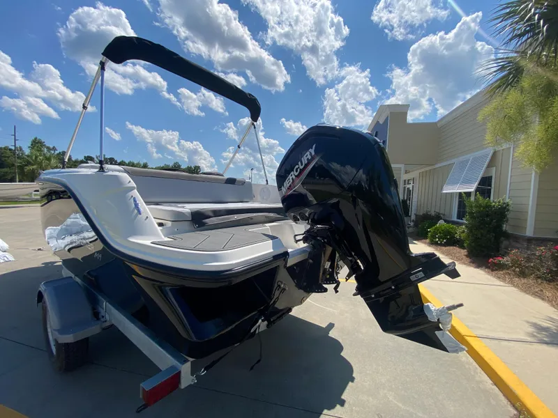 Slide: The Image of 2024 Bayliner Element M19 boat with Mercury outboard motor, parked outdoors on a sunny day. - 2