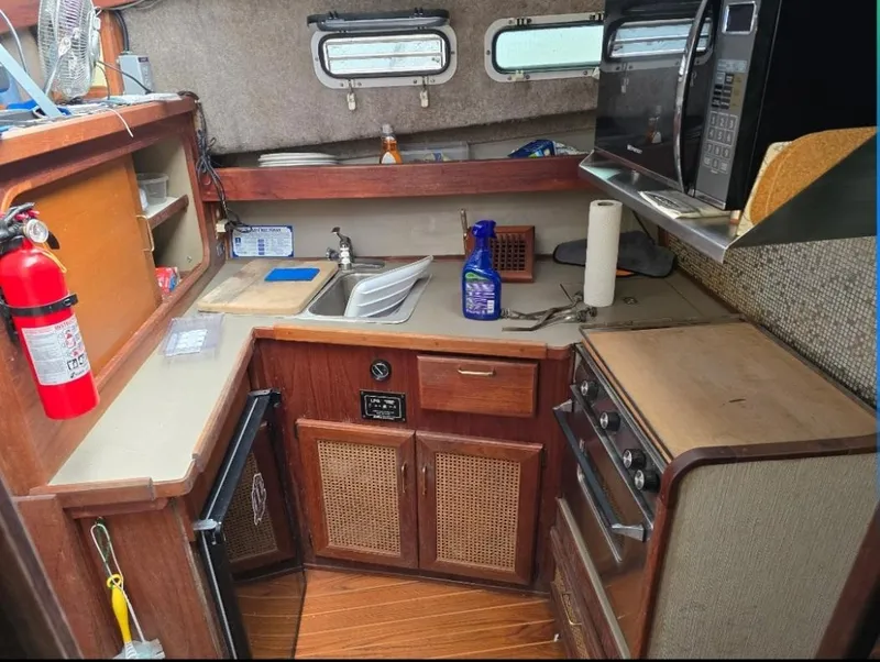 Slide: The Image of 1984 Bayliner 3270 Command Bridge kitchen with stove, sink, and microwave. - 16
