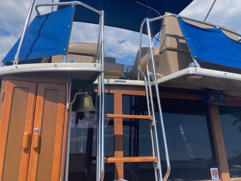 Slide: The Image of 1984 Bayliner 3270 Command Bridge with blue canvas covers and wooden ladder. - 8