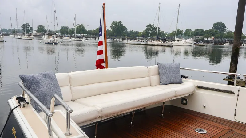 Slide: The Image of 2010 MJM 40z Downeast boat with white seating and American flag in a marina. - 15