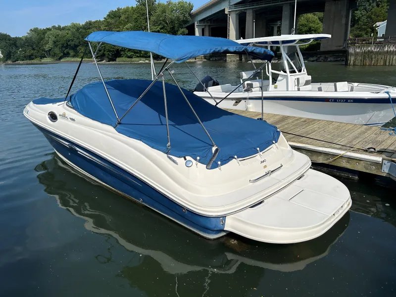 Slide: The Image of 2007 Sea Ray 240 Sundeck boat with blue canopy docked on calm water. - 13