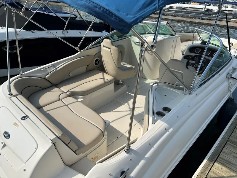 Slide: The Image of 2007 Sea Ray 240 Sundeck boat with beige seating and blue canopy at dock. - 2