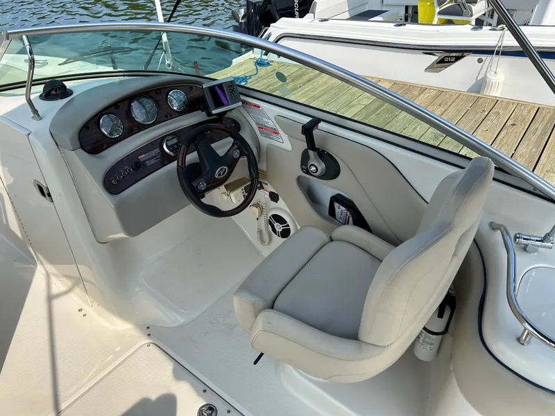 Slide: The Image of 2007 Sea Ray 240 Sundeck helm with steering wheel and gauges, docked by water. - 7