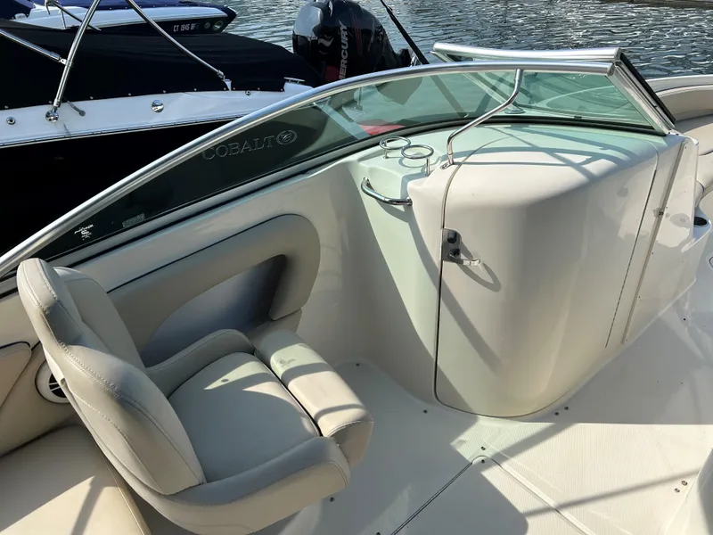 Slide: The Image of 2007 Sea Ray 240 Sundeck interior with seating and windshield, docked by the water. - 9