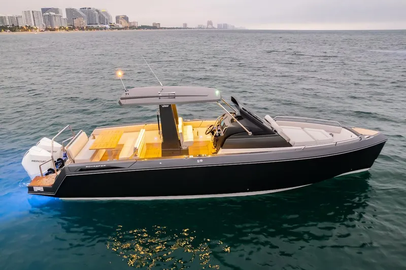 Slide: The Image of Schaefer V33 2025 luxury motorboat cruising near a city shoreline at dusk. - 30