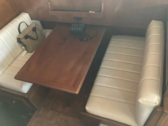 Slide: The Image of 1987 Viking Convertible boat interior with wooden table and white cushioned seating. - 10