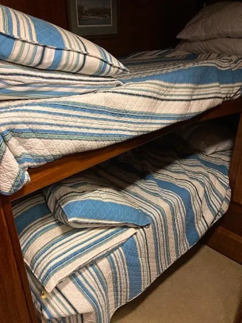 Slide: The Image of Bunk beds with blue striped bedding in a 1987 Viking Convertible boat. - 16