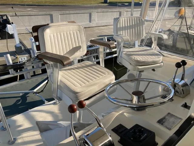 Slide: The Image of 1987 Viking Convertible boat helm with two white captain's chairs and steering wheel. - 5